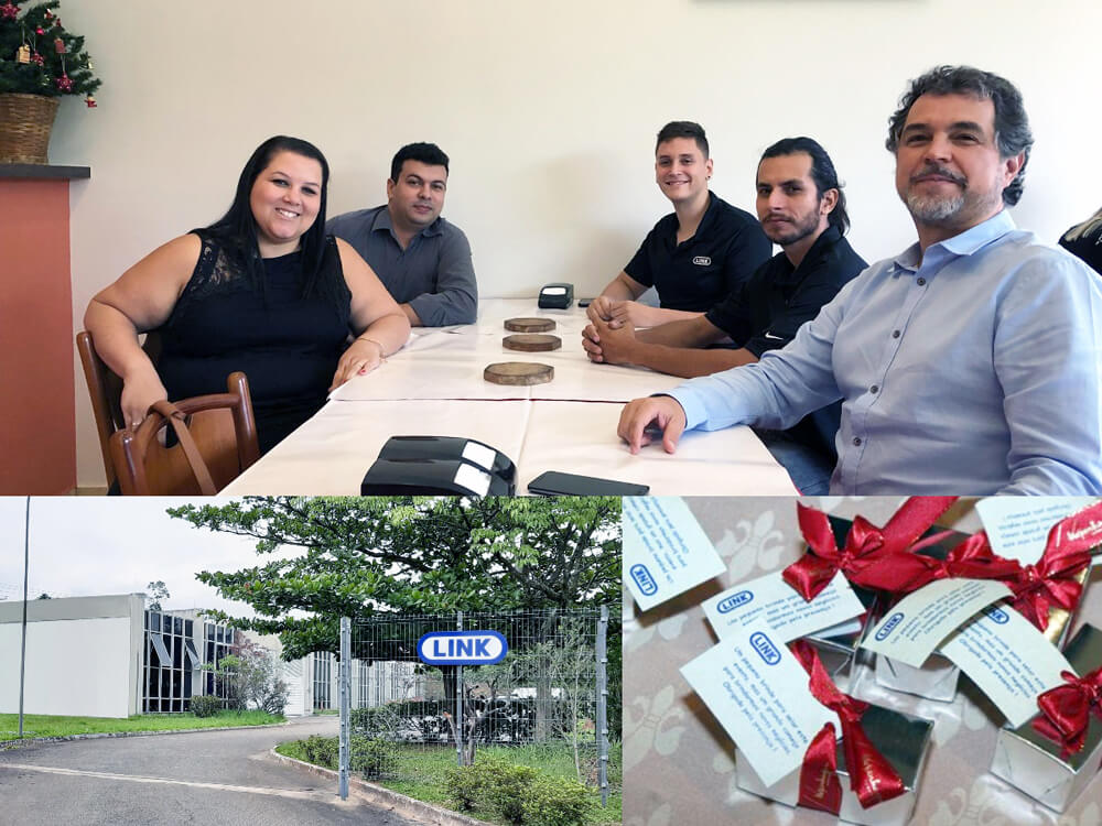 Team members pose for a picture around a table as they celebrate the LINK Brazil 15th Anniversary.